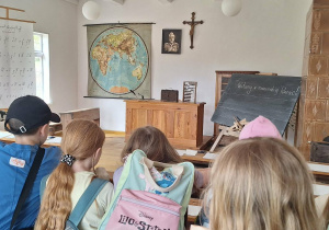 Dzieci oglądaja eksponaty znajdujące się w chacie.