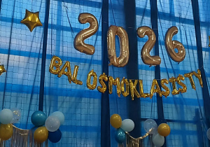 2026 Bal Ósmoklasisty - ozdobny napis z balonów w kolorze złotym wisi na oknach.
